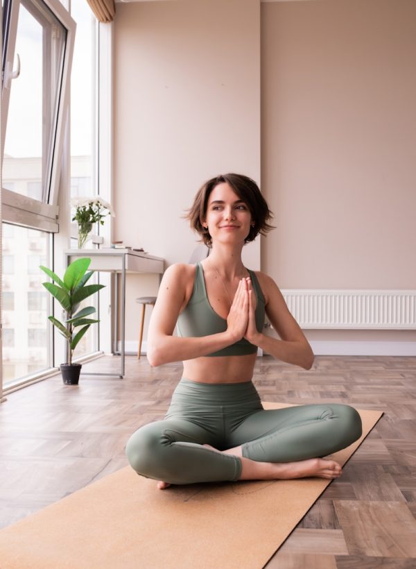 a woman sitting on a yoga mat in a room